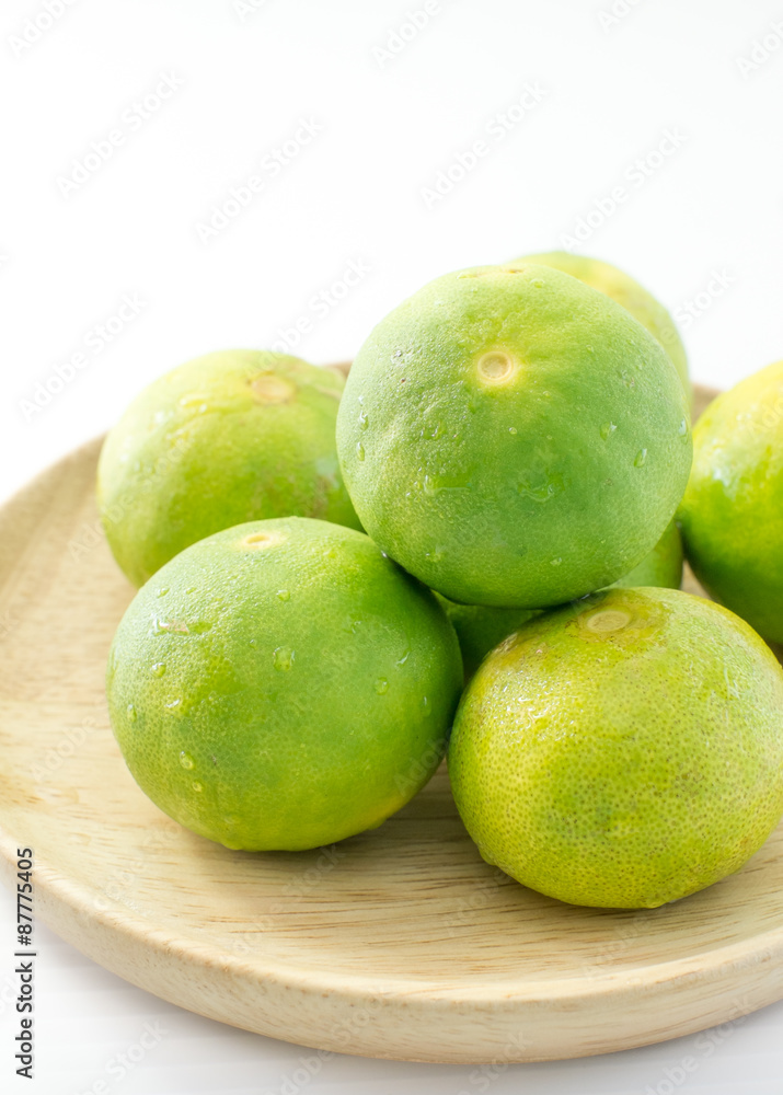 Limes on wooden dish on white background Limes on wooden dish on white background
