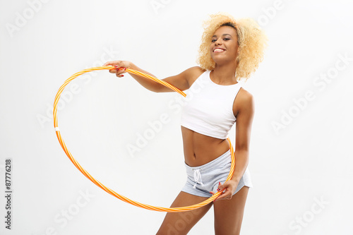 Hula hoop, sposób na szczupłą talię. Kobieta trenuje z kołem hula hoop 
