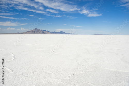 Dramatic white desert background of textured salt formations with rugged mountain range on the horizon