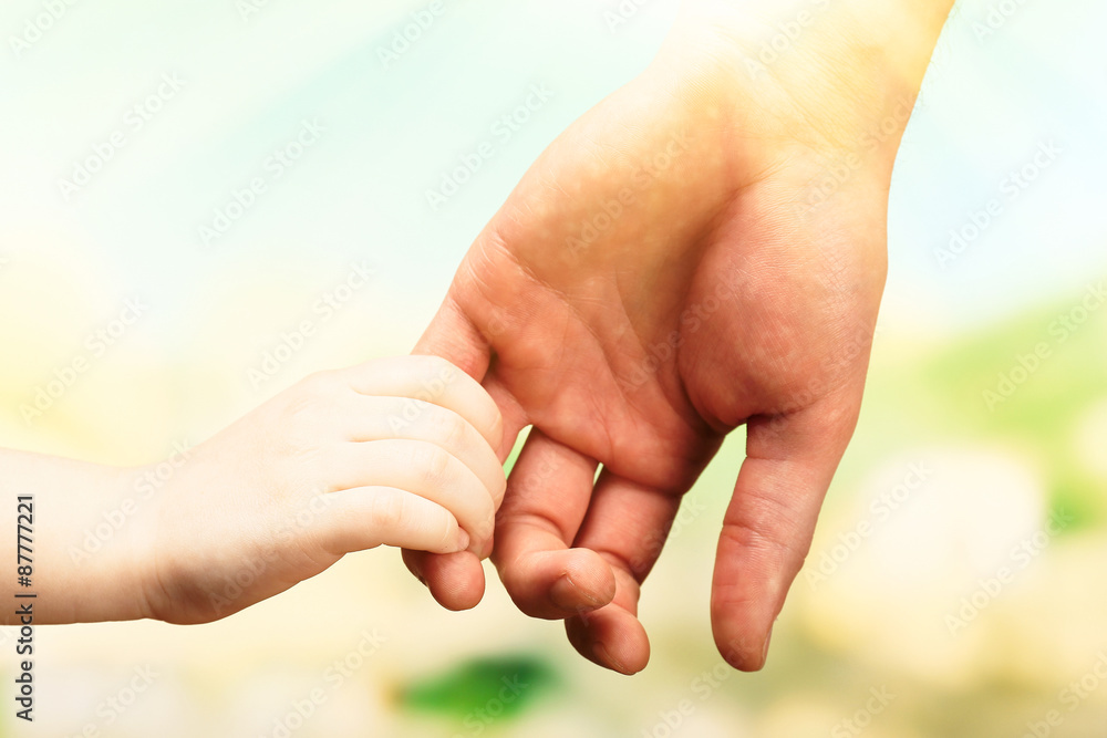 Child and mother hands together on bright background Child and mother hands together on bright background