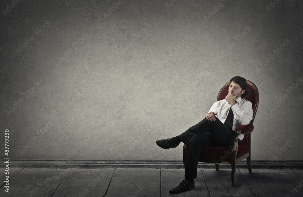 Young businessman sitting in a red chair Young businessman sitting in a red chair