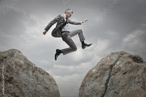 Manager jumping from a rock to another
