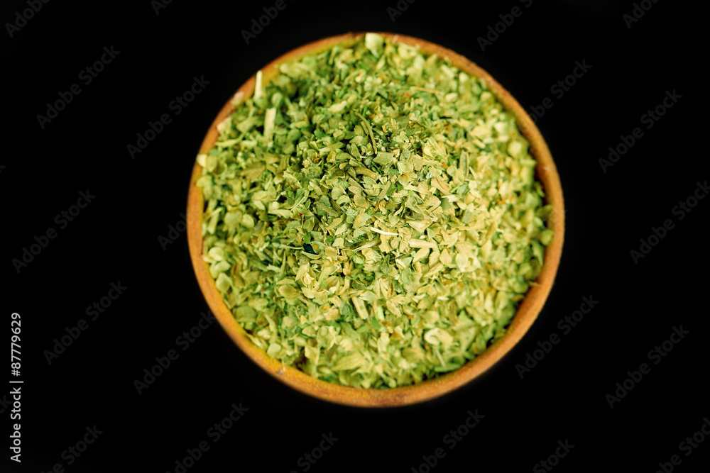 Dried parsley in wooden bowl, on black background Dried parsley in wooden bowl, on black background