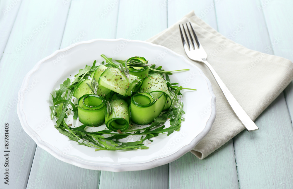 Plate of green salad with cucumber, arugula and rosemary on wooden table, closeup Plate of green salad with cucumber, arugula and rosemary on wooden table, closeup