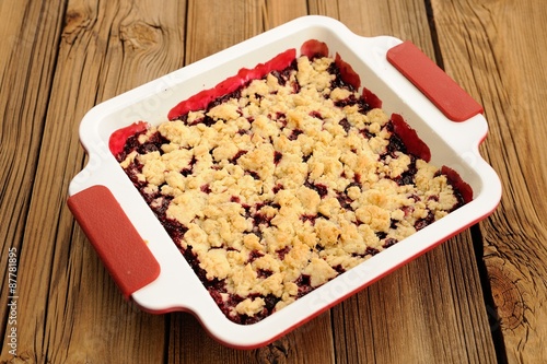 Tasty homemade cherry oat crumble in square white baking dish on