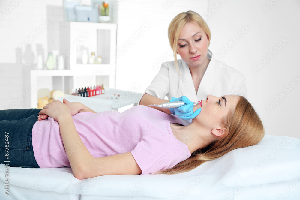 Cosmetologist applying permanent make up on lips Cosmetologist applying permanent make up on lips