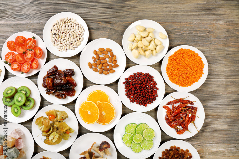 Different products on saucers on wooden table, top view