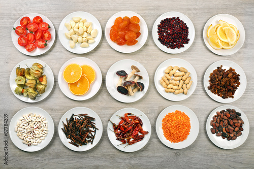 Different products on saucers on wooden table, top view