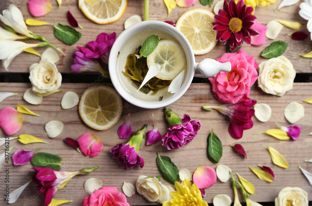 Cup of herbal tea with beautiful flowers, on wooden background