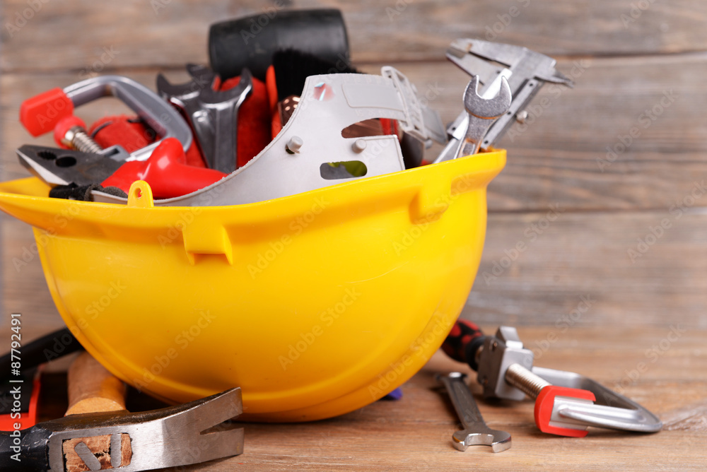 Construction tools in helmet on wooden background