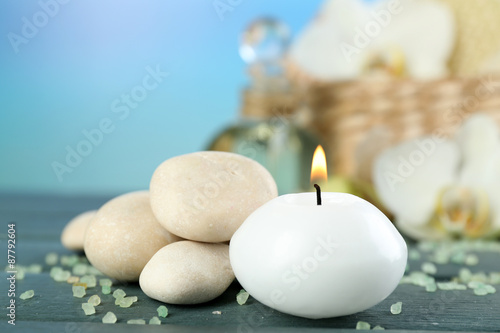 Still life with candle, pebbles and  spa treatment on wooden table, on bright background