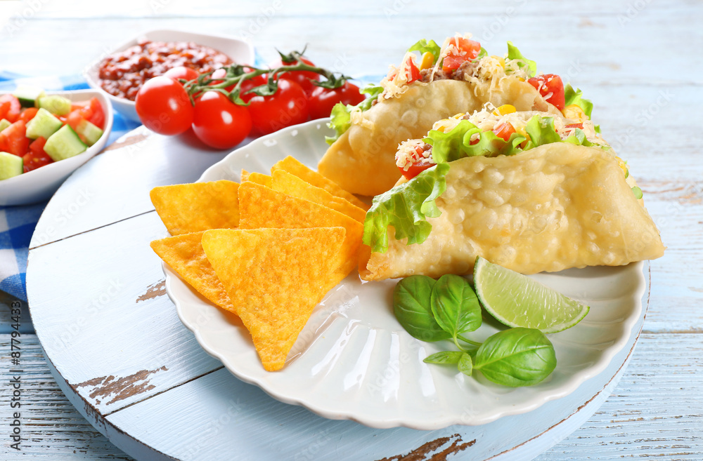 Tasty taco with nachos chips and vegetables on plate on table close up Tasty taco with nachos chips and vegetables on plate on table close up