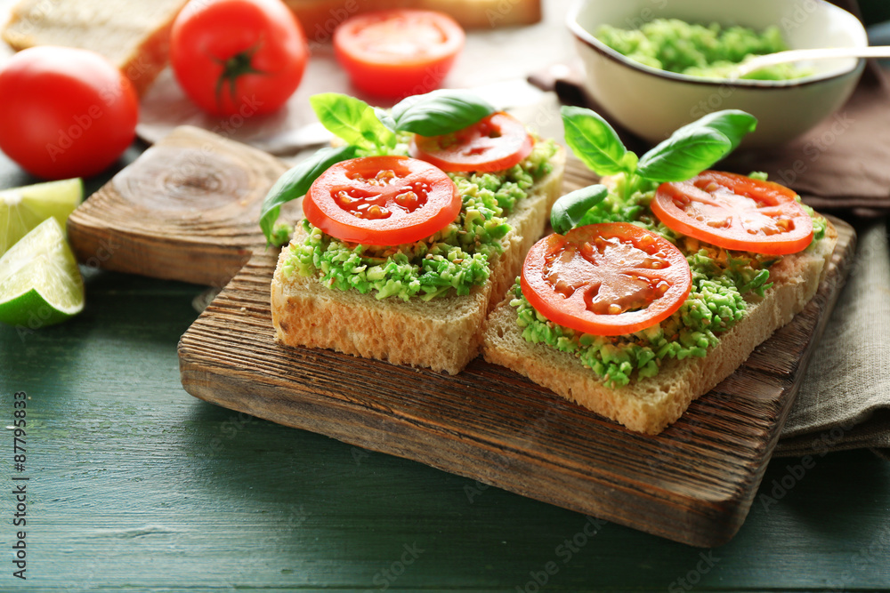 Vegan sandwich with avocado and vegetables on cutting board, on wooden background Vegan sandwich with avocado and vegetables on cutting board, on wooden background