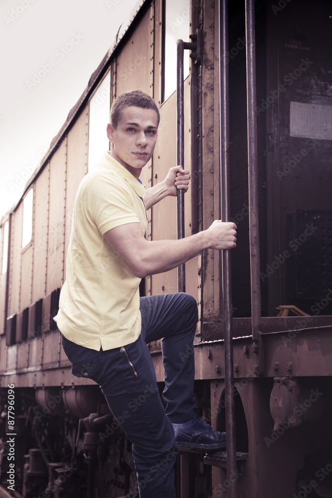 Fit guy with polo shirt hanging from old train, jumping Fit guy with polo shirt hanging from old train, jumping