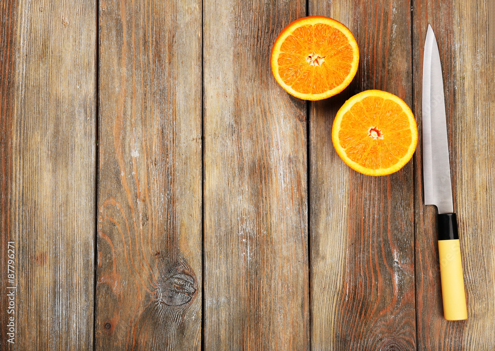 Halves of orange with knife on wooden background Halves of orange with knife on wooden background