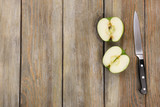 Halves of apple with knife on wooden background