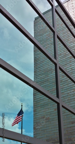 American flag reflecting in glass window of modern building