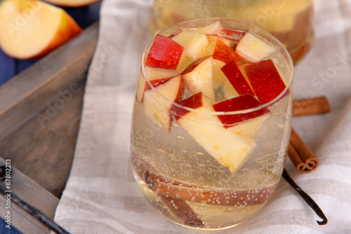 Glass and carafe of apple cider with fruits and spices on table close up