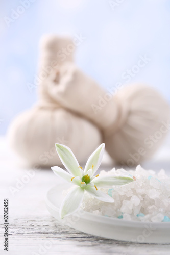 Sea salt  flowers and spa treatment on color wooden table  on light background