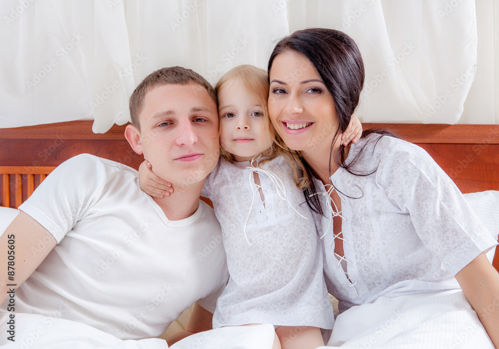 Happy family lying on a bed together in the bedroom Happy family lying on a bed together in the bedroom