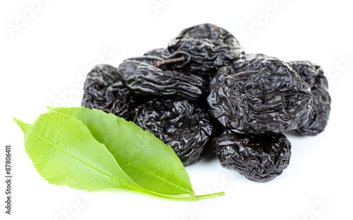 Pile of prunes with green leaves isolated on white
