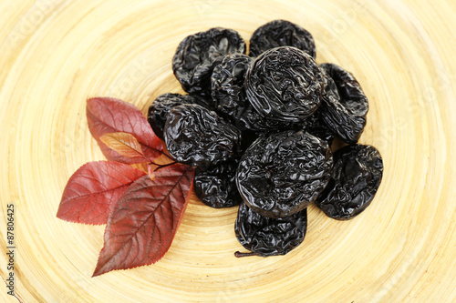 Pile of prunes with leaves on wooden background