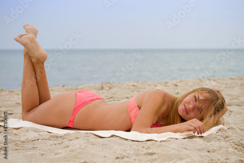 Young beautiful girl in bikini sunbathing on the beach; freedom summertime concept