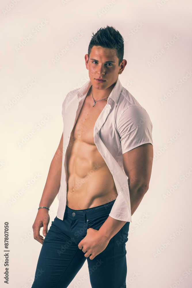 Young man displaying his muscular torso holding open his stylish Young man displaying his muscular torso holding open his stylish