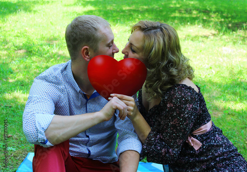 Young loving couple looking at each other and holding a red heart. love story