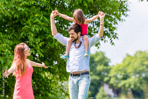 Familie - Vater trägt Kind auf der Schulter auf einem Spaziergang