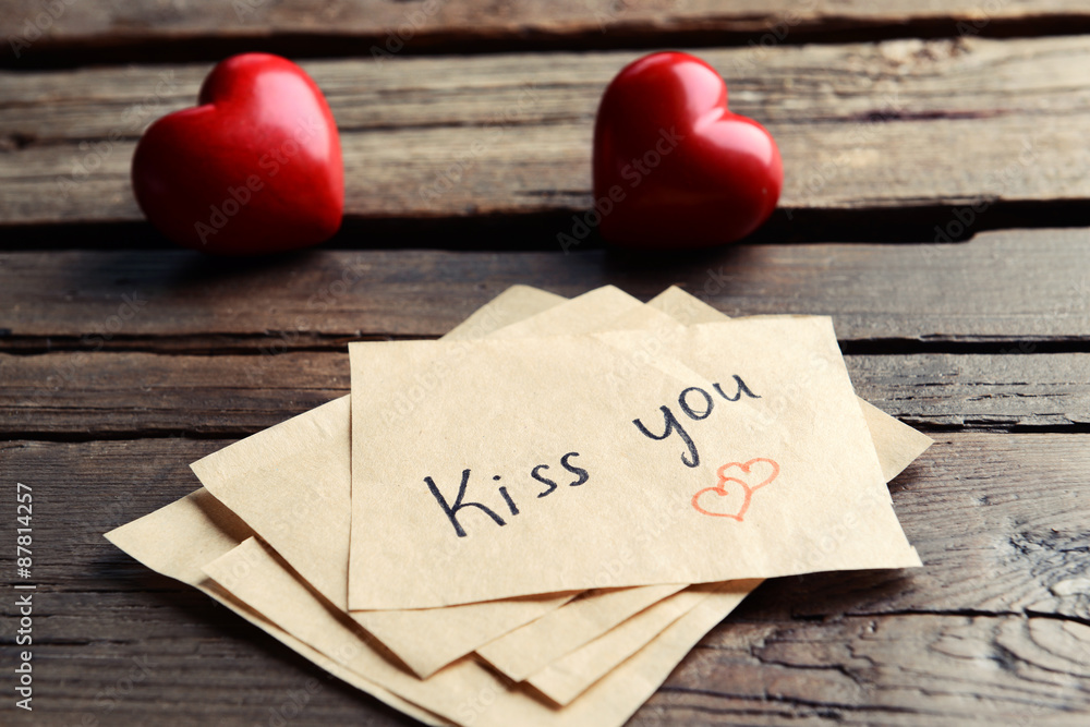 Written message with decorative hearts on wooden table close up Written message with decorative hearts on wooden table close up