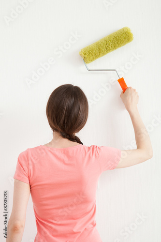 Young woman painting a white wall