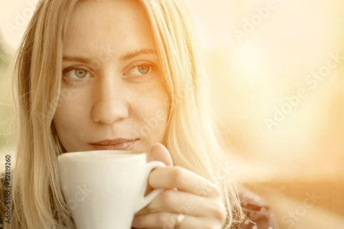 Female with coffee at cafe under sunlight