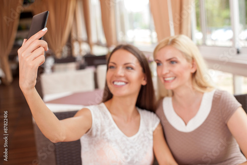 Cheerful young woman are making selfie in cafe