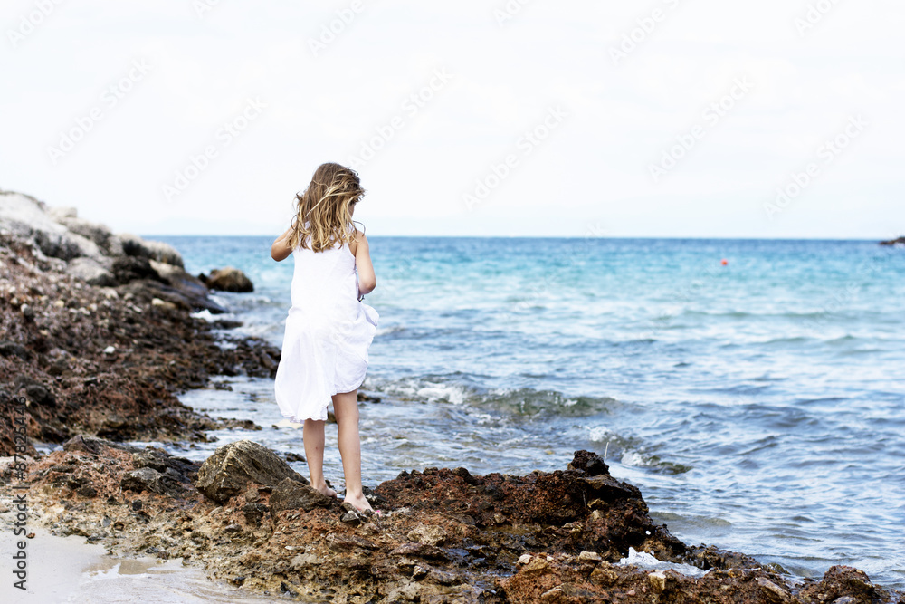 Little girl in white dress on beach