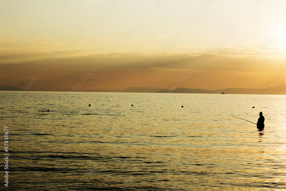 Fisherman in the sea at sunset