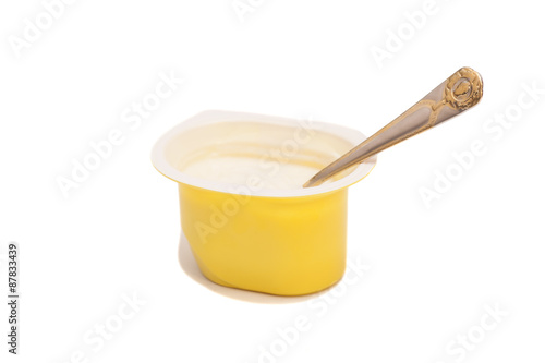 Peach yoghurt in open plastic cup with spoon isolated on white