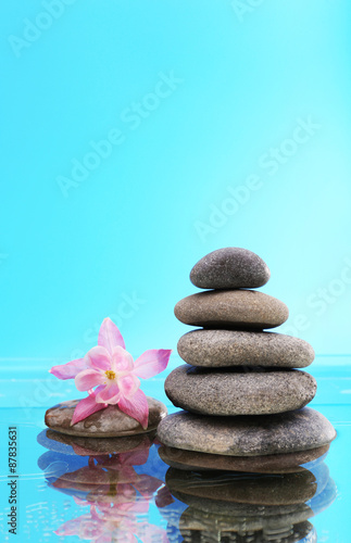 Stack of spa stones with flower on blue background