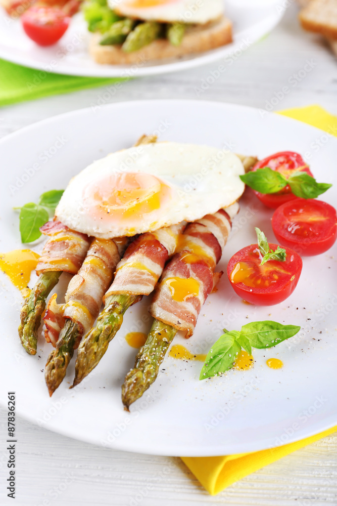 Dish of asparagus with bacon and egg in plate on table, closeup Dish of asparagus with bacon and egg in plate on table, closeup