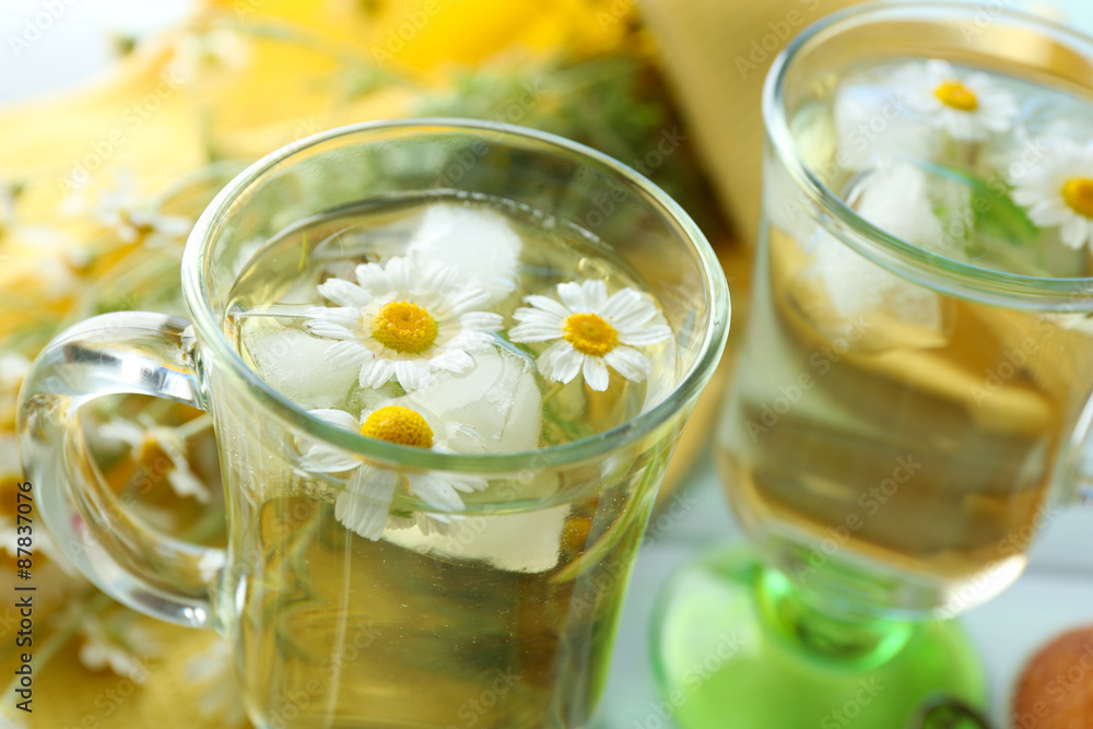 Glasses of chamomile tea with chamomile flowers on color wooden background Glasses of chamomile tea with chamomile flowers on color wooden background