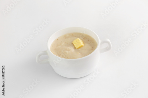 Bowl of semoline porridge with piece of butter isolated