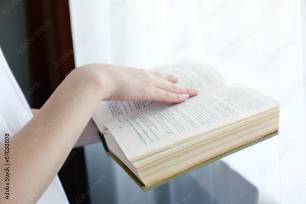 Obraz premium Young woman's hand resting on open book pages, reading and learning concept, education and knowledge acquisition