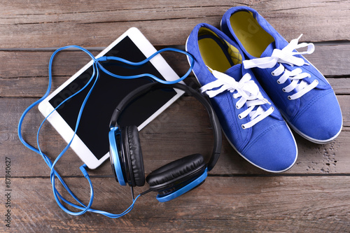 Headphones with sneakers and tablet on wooden background