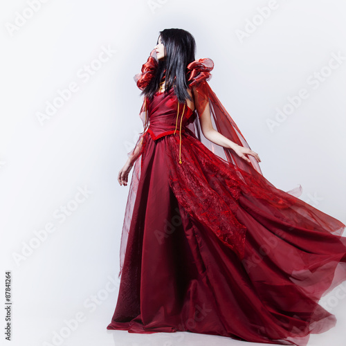 Fashion photo of young magnificent woman in red dress. Studio