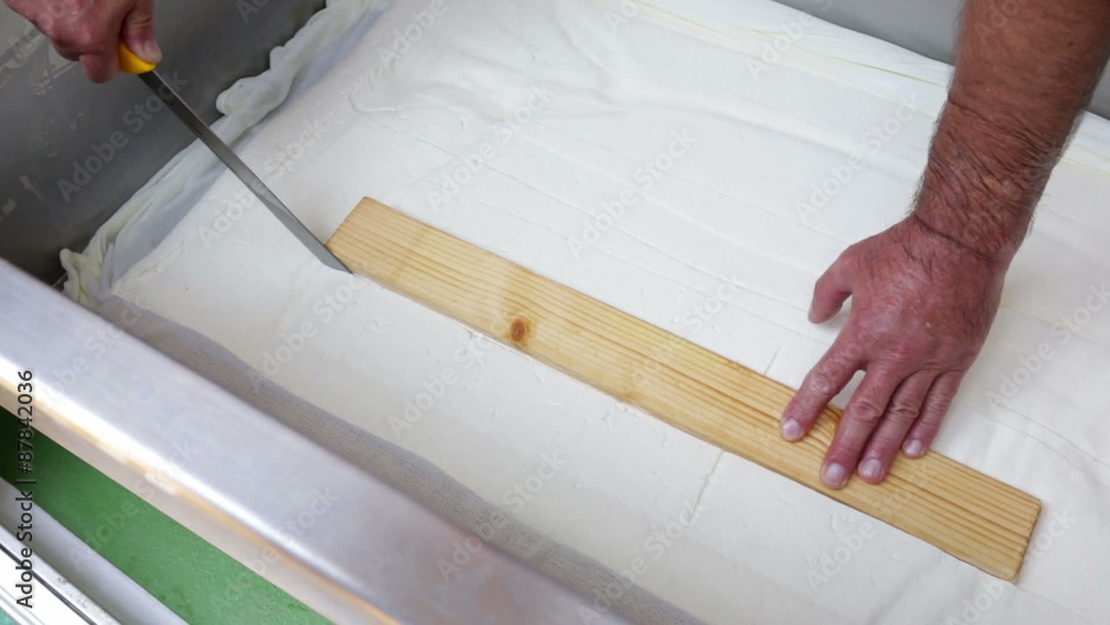 The process of producing tasty traditional white Bulgarian feta cheese at its final stage before packeting. Cutting cubes with a knife. The process of producing tasty traditional white Bulgarian feta cheese at its final stage before packeting. Cutting cubes with a knife.