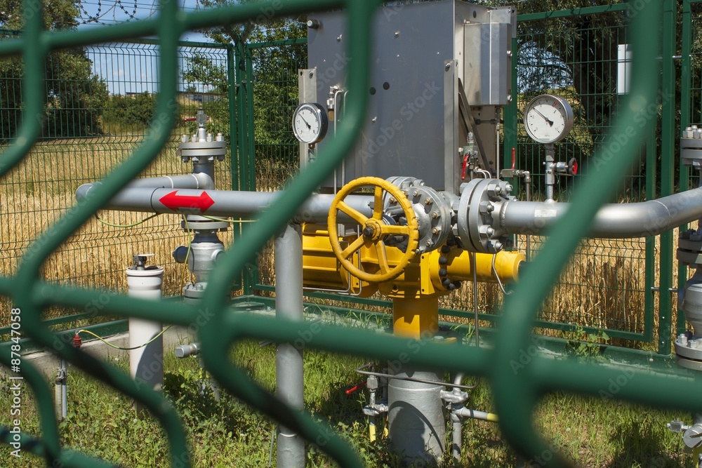 Checkpoint pipeline, pressure measurements and flow of natural gas. Closeup of pressure meter on natural gas pipeline. Fenced station located in the fields against blue sky.

