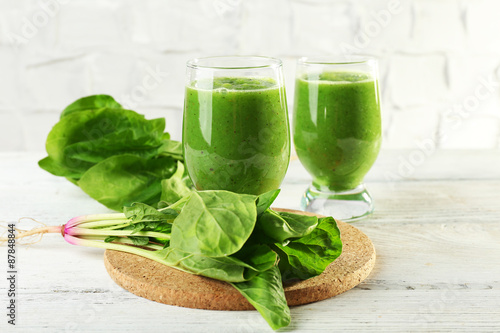 Healthy green smoothie with spinach on wooden table on white wall background