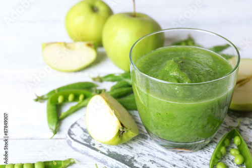 Healthy green smoothie with peas and apples on wooden table, closeup