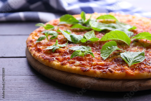 Pizza with basil on wooden table, closeup