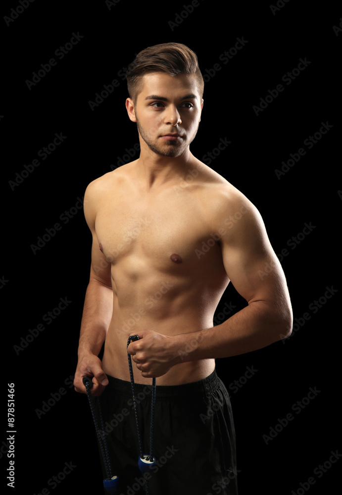 Fototapeta premium Muscle young man exercising with resistance band on dark background